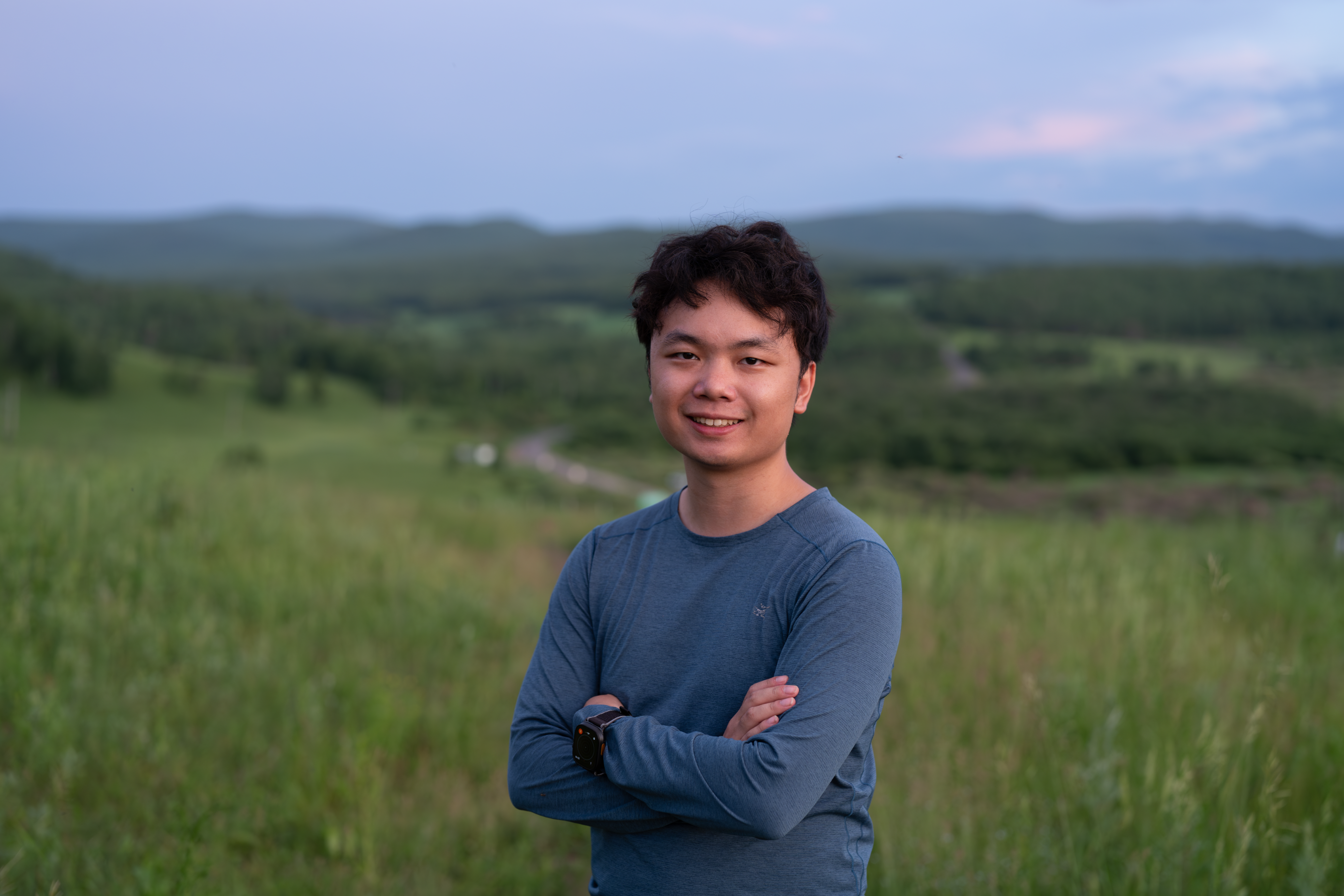 Zhiyu Wang outdoors in a green mountain landscape